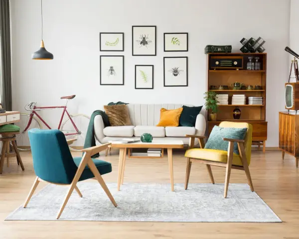 Wohnzimmer im 60er Jahre Style mit Retro-Möbeln, einem Fahrrad und Insektenbildern an der Wand.
