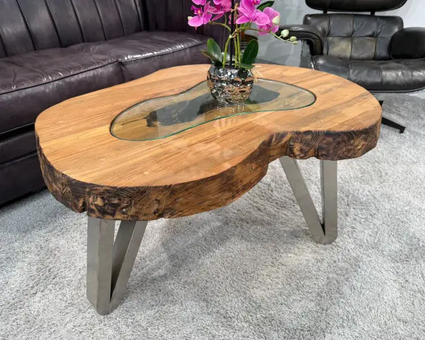 Ein Couchtisch aus massivem Holz mit Glasplatte und Metallbeinen. Die Höhe ist ideal, um Getränke und Snacks bequem zu erreichen.
