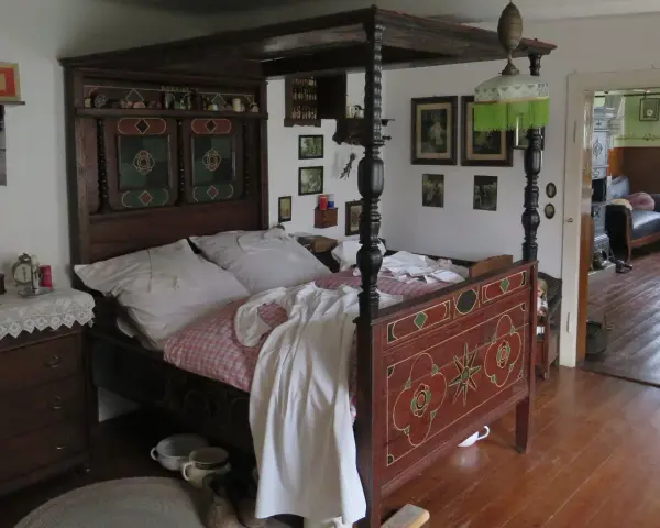 Ein prachtvolles Himmelbett im mittelalterlichen Stil, mit kunstvollen Schnitzereien und einem karierten Bettzeug.