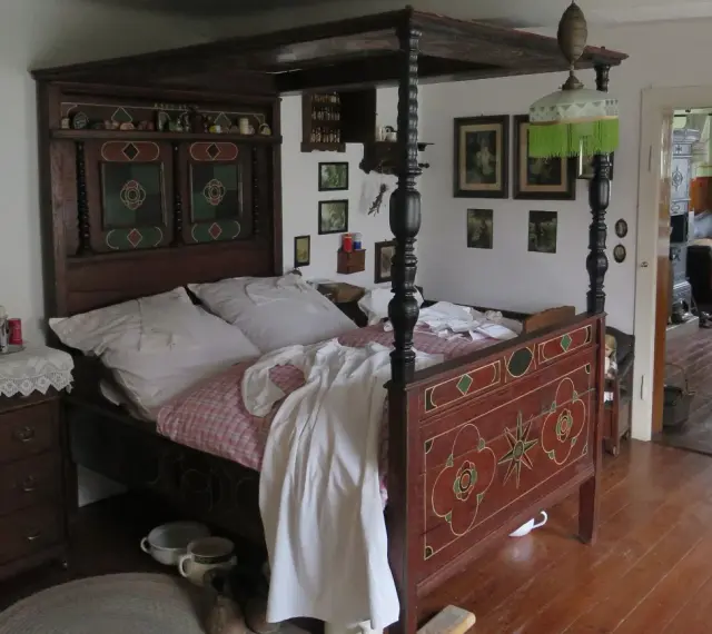 Ein prachtvolles Himmelbett im mittelalterlichen Stil, mit kunstvollen Schnitzereien und einem karierten Bettzeug.