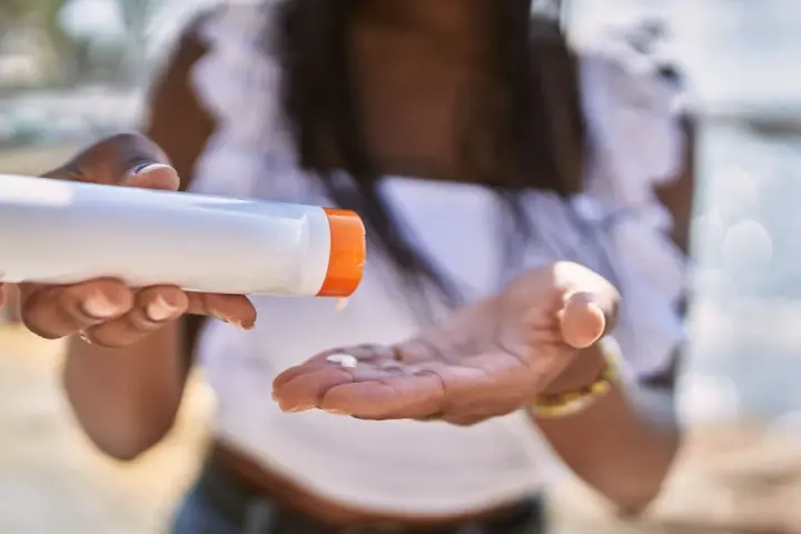 Frau gibt Sonnencreme auf ihre Hand. So vermeidet sie Sonnencreme Flecken auf Kleidung.