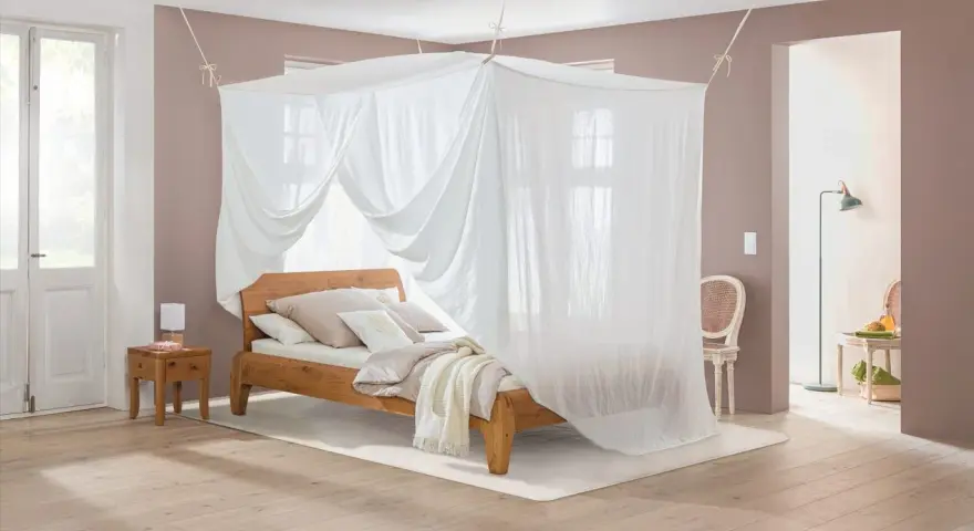 Ein gemütliches Schlafzimmer mit Himmelbett und Moskitonetz, das vor Elektrosmog schützt.