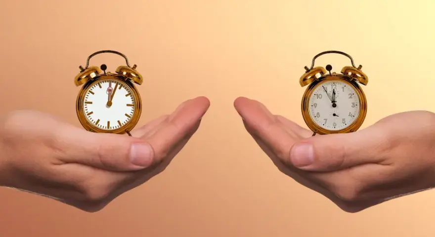 Zwei Hände halten je einen Wecker. Die Frage ist: wann aufstehen?