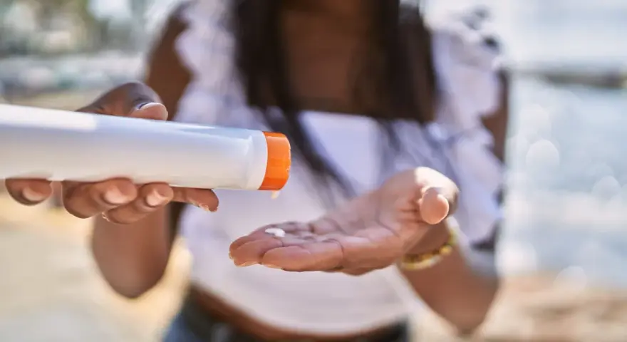 Frau gibt Sonnencreme auf ihre Hand. So vermeidet sie Sonnencreme Flecken auf Kleidung.
