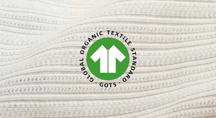 Das GOTS-Zertifikat auf weißem, geripptem Stoff. Es steht für Global Organic Textile Standard und garantiert nachhaltige Textilien.