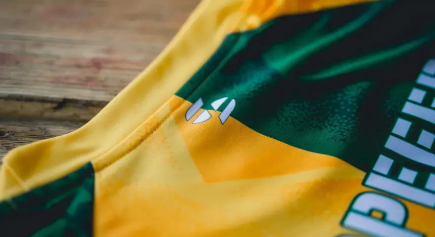 Nahaufnahme eines gelb-grünen **jersey polyester** mit einem weißen Logo.