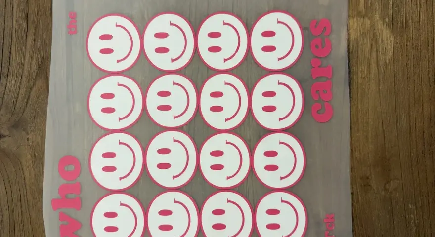 Aufkleber mit Smiley-Gesichtern, bereit für das Textildruck-Verfahren. "Who the cares rck" steht auf dem Transferpapier.
