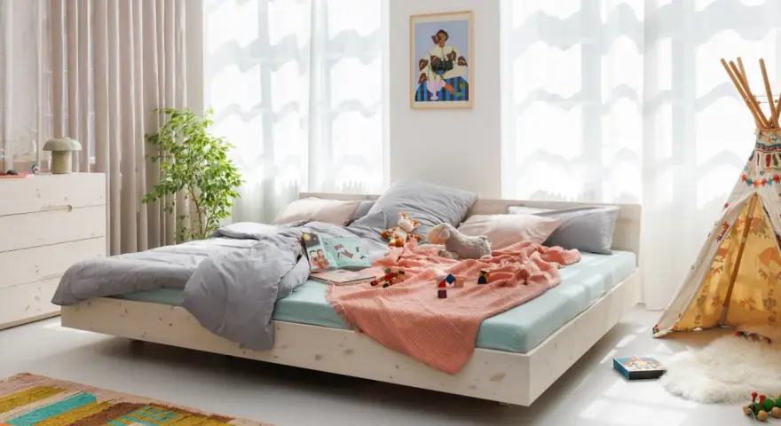 Ein gemütliches Familienbett mit Spielzeug und Kuscheltieren, das zum Kuscheln einlädt. Hier ist Platz für die ganze Familie.