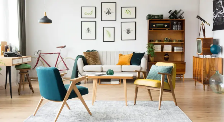 Wohnzimmer im 60er Jahre Style mit Retro-Möbeln, einem Fahrrad und Insektenbildern an der Wand.