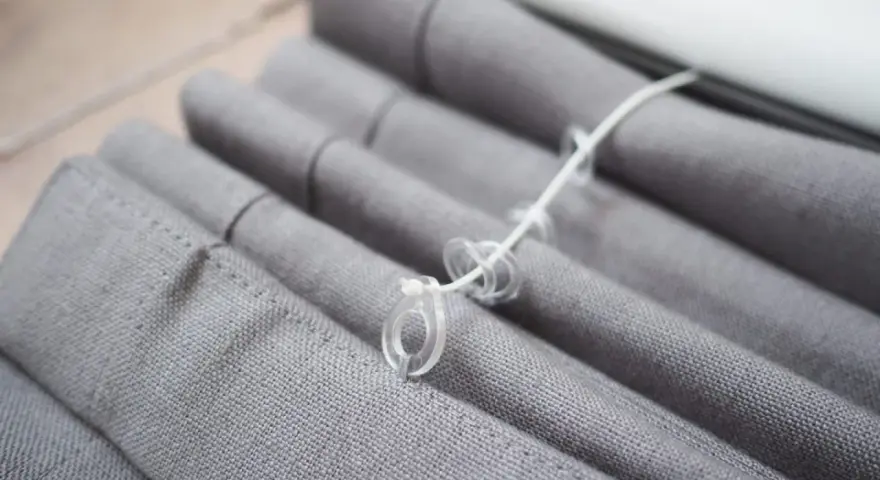 Grauer Raffrollo Stoff mit Schnüren und Ringen, bereit zum Raffrollo waschen.
