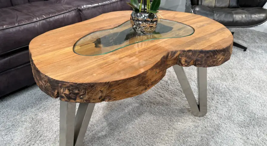 Ein Couchtisch aus massivem Holz mit Glasplatte und Metallbeinen. Die Höhe ist ideal, um Getränke und Snacks bequem zu erreichen.