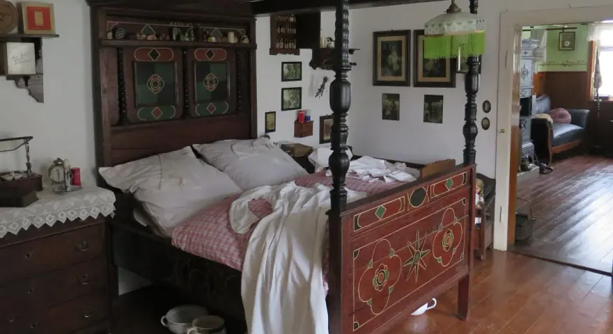 Ein prachtvolles Himmelbett im mittelalterlichen Stil, mit kunstvollen Schnitzereien und einem karierten Bettzeug.