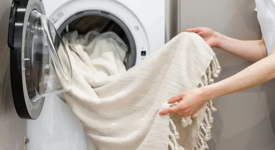 Helle Gardinen werden in die Waschmaschine geladen. Mit Backpulver werden sie wieder strahlend weiß.