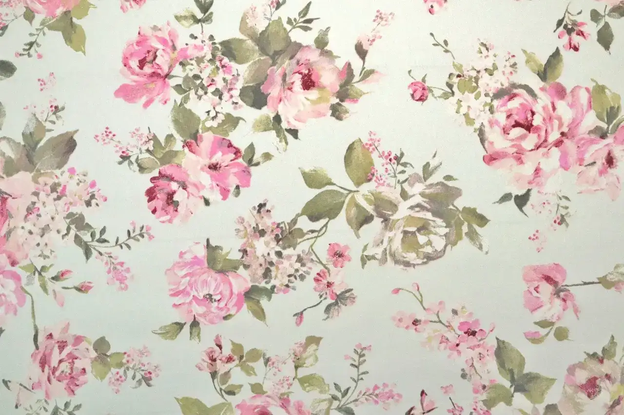 Zarte Stoffe mit einem romantischen Blumenmuster im Vintage-Stil. Rosa und cremefarbene Bl&uuml;ten mit gr&uuml;nen Bl&auml;ttern auf hellem Hintergrund.