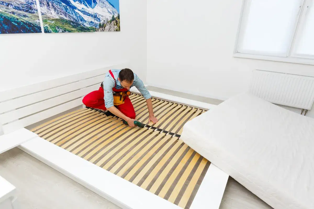 Mann repariert Lattenrost, damit das Bett nicht mehr quietscht.
