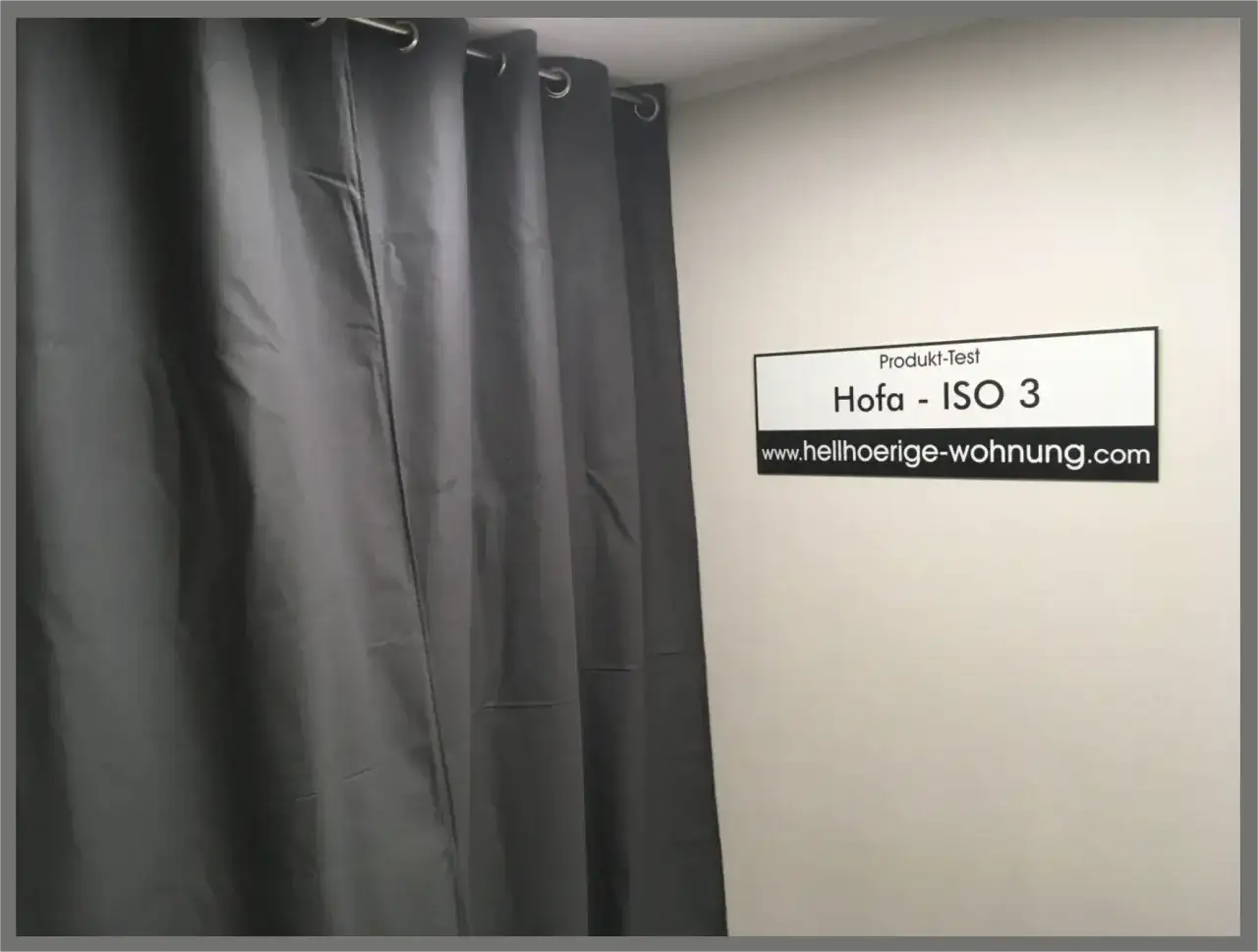Grauer Schallschutz Vorhang im Test. Das Schild zeigt