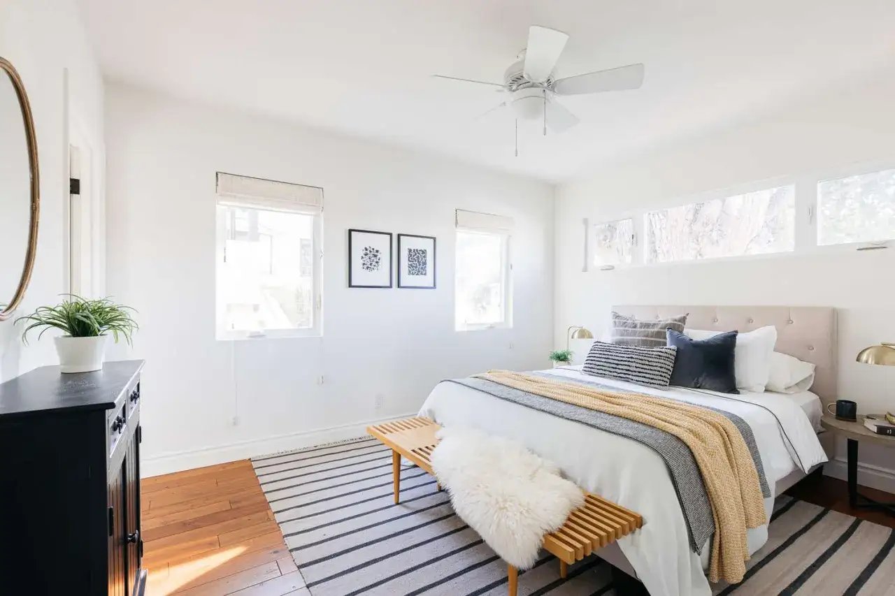 Helles Schlafzimmer mit Bett, Deckenventilator und Fensterfront. Hier kann man entspannt schlafen, ohne Elektrosmog.