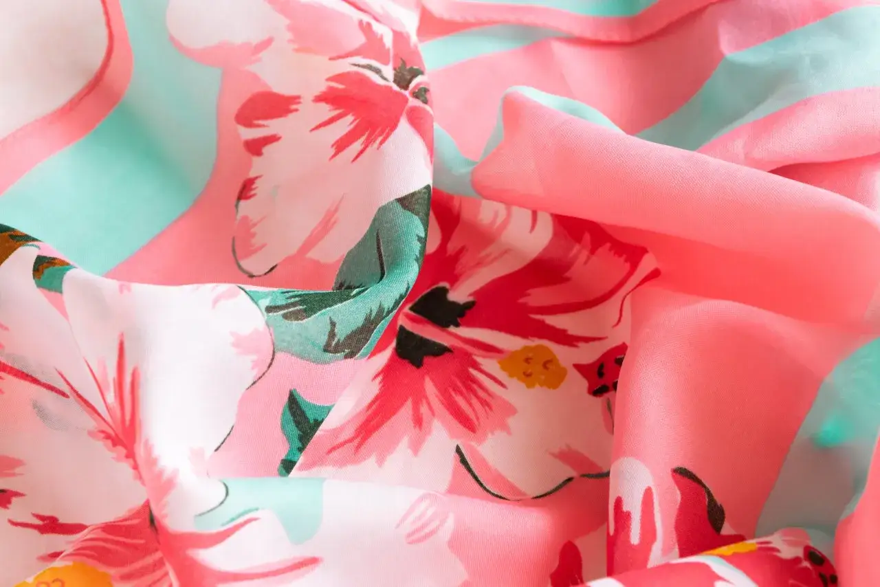 Ein zartes, fließendes Textil mit einem lebendigen Blumenmuster in Pink und Türkis. Der digitaldruck textil zeigt detailreiche Blüten, die auf dem Stoff wie gemalt wirken.