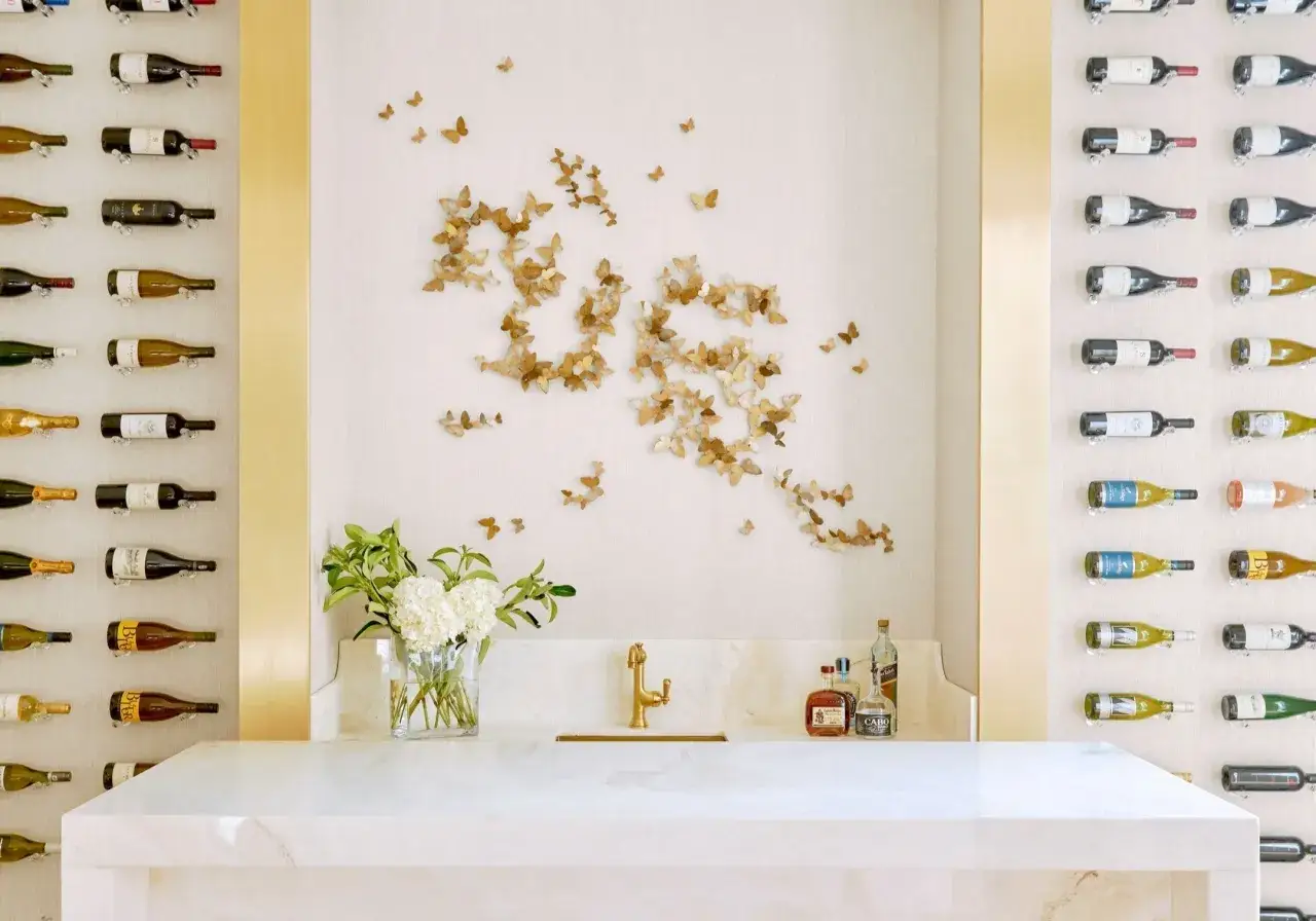 Ein schmetterling muster ziert die Wand &uuml;ber einem goldenen Wasserhahn und einer Marmorbar. Weinregale flankieren die Szene.