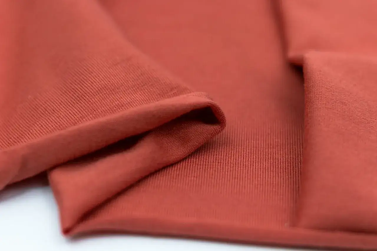 Roter Stoff, was ist Single Jersey? Glatt und weich, mit feinen Rippen auf der Rückseite, ideal für bequeme Kleidung.
