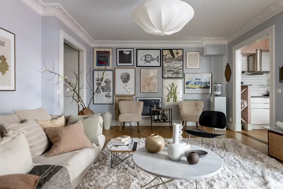 Gem&uuml;tliches Wohnzimmer mit vielen Bildern an der Wand, die nordische Muster und botanische Motive zeigen. Ein beiger Teppich und eine Couch laden zum Entspannen ein.