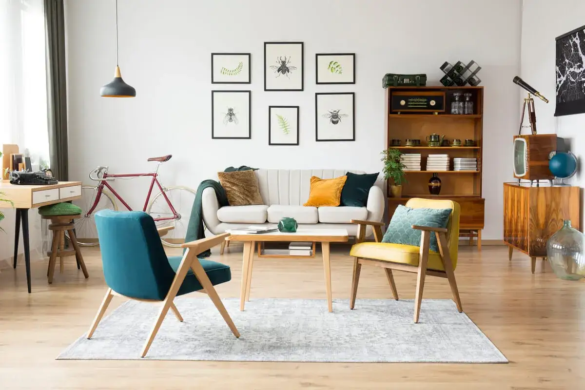 Wohnzimmer im 60er Jahre Style mit Retro-M&ouml;beln, Vintage-Fahrrad und Insekten-Bildern an der Wand.