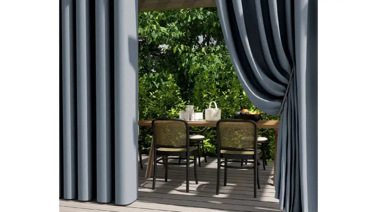 Graue Vorhänge aus Polyesterstoff rahmen eine Terrasse mit Tisch und Stühlen ein.
