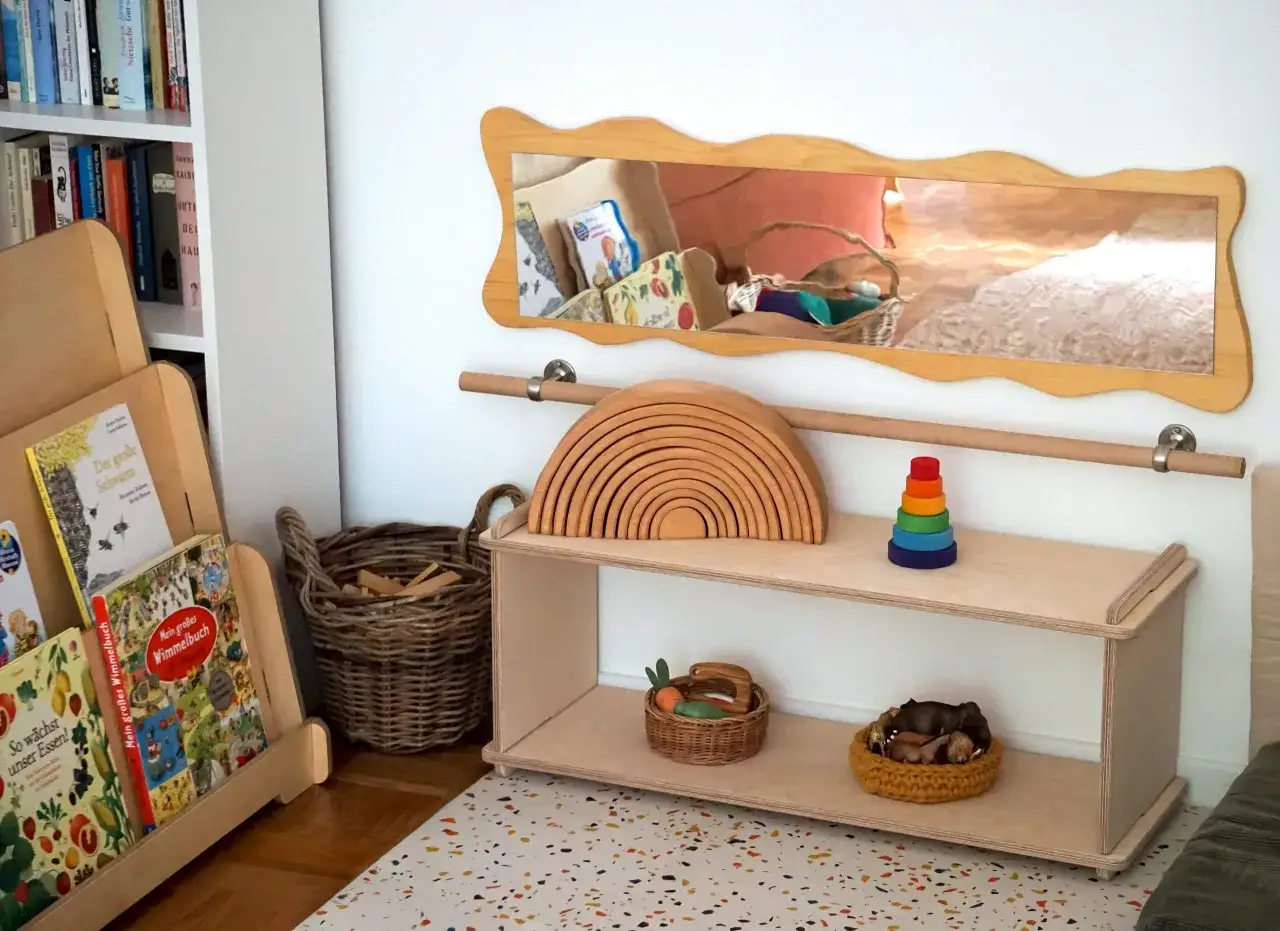 Ein helles, freundliches Montessori Kinderzimmer mit Holzspielzeug, B&uuml;chern und K&ouml;rben. Ein Regenbogen aus Holz und ein Stapelturm laden zum Spielen ein.