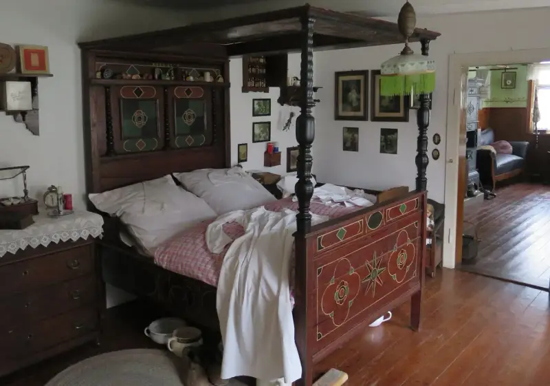 Ein prachtvolles Himmelbett im mittelalterlichen Stil, mit kunstvollen Schnitzereien und einem karierten Bettzeug.